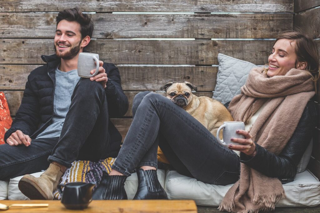 merry christmas, man, woman, dog, pet, pug, owners, couple, relationship, warm clothes, cozy, scarf, jackets, jeans, boots, fashion, people, happy, love, female, young, male, adult, caucasian, happiness, romantic, portrait, smile, smiling, girlfriend, date, boyfriend, together, person, lovers, sitting, relaxing, rustic, cushions, couch, laughing, animal, enjoying, coffee