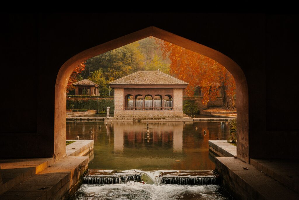 Serene autumn scene of Mughal garden architecture reflected in water at Achabal, Kashmir.